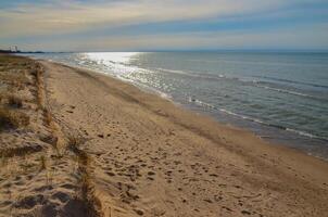 Sand dunes on the shore of a large lake, reflection of the sun in the water. Indiana Dunes National Lakeshore, USA photo