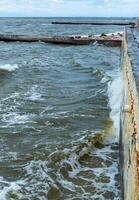 The sand of the beach in Odessa washed into the sea, the water beats against the protective wall photo