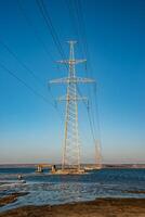 High-voltage power line against the background of the blue sky above the water of the lake photo
