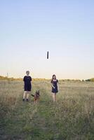two women play in the field with a german shepherd dog toy at sunset photo