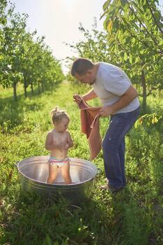 un papá envuelve, abrazos y Besos su niñito después un bañera foto
