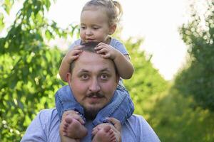 a father plays with a toddler on his shoulders photo