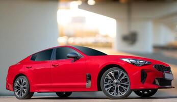 A red car on a background of city environment. Stylish, modern, bright image of the car for design solutions. photo