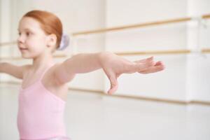 Young ballet girl at studio lesson. Training performance. Stretching exercise pose. Ballerina practice balance technique. Classical elegance fitness. Dancing costume. Close up. Pink dress, skirt photo