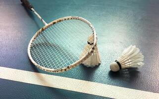 Cream white badminton shuttlecock and racket with neon light shading on floor in indoor badminton court, copy space, soft and selective focus. photo