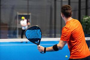 unrecognizable padel player playing padel in a padel court indoor behind the net photo