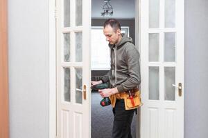 Locksmith, man and maintenance, handyman with home renovation and fixing, change door locks with power tools. Construction, building industry and trade with manual labour, vocation and employee photo