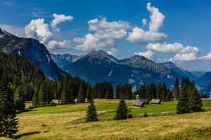 Panoramic view of idyllic summer landscape in the Alps with clear mountain lake and fresh green mountain pastures in the background photo