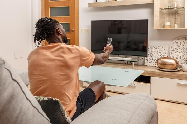 Young Man Relaxing on Couch While Watching Television in Cozy Living Room
