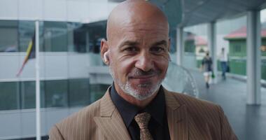 Businessman in formal suit and wireless headphones into wide smile. Wireless headphones speak about modernity and mobility. Headphones in harmony with modern skyscraper creating image business person. video