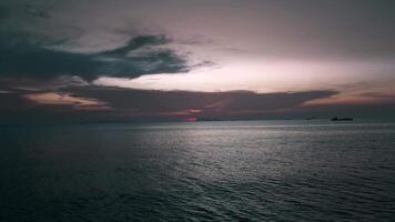 Cinematic drone fly at early morning time over dark sea water before sun rising with beautiful red sky. Aerial view drone fly over ocean water before sunrise. Dawn over the sea. Beginning of new day video