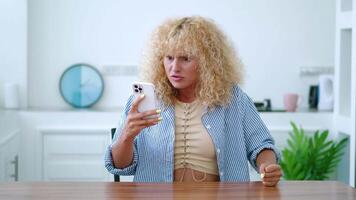Shocked furious anxious enraged Caucasian redhead curly-haired woman using mobile phone, scrolling news feed, experiencing rage and anger, feeling anxious, enraged, answers to a shocked message video