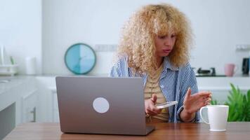 Overworked multitasking busy curly-haired blonde woman freelancer, entrepreneur, copywriter, journalist working on smartphone and typing text on laptop at the same time while working on new project video