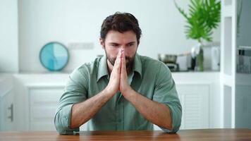 Anxious Caucasian guy, freelancer sitting at the kitchen table in the home interior, experiencing panic attacks and stress due to problems with business, trying get out of a hopeless situation video