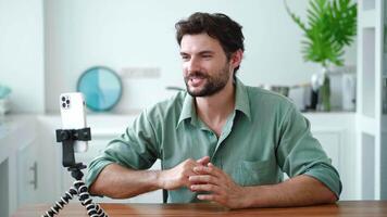 Adorable young man, cutely smiling a cheerful toothy smile while talking with his interlocutor by link. Freelancer having a dialogue with clients. Smart student studying online during quarantine video
