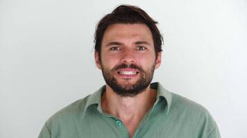 Handsome young bearded man looks at camera with uncertainty and expectation, then suddenly rejoices and clenches his fists from what he saw or good news, smiling with a cheerful beautiful toothy smile video
