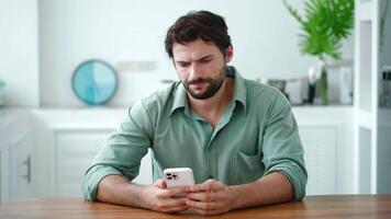 Bad sms news, device problem, mobile app crash concept. Young Hispanic man using smartphone, reads negative messages or scrolls bad news feels annoyed. Annoyed guy having gadget troubles video