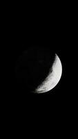 The partially sun-drenched lunar landscape in view from above, vertical video