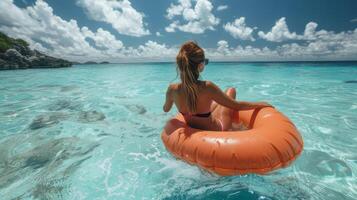 Young Woman Relaxing on an Orange Lilo in Crystal-Clear Sea Waters photo