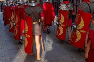Roman legionaries with metal armor and shield at a historical reenactment event seen from the back. photo