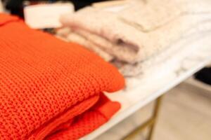 selective focus, red and white wool sweaters folded on a store shelf photo