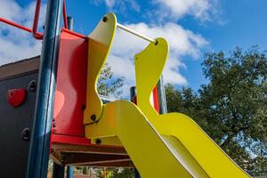 detail of a yellow and red slide in a playground in fall photo