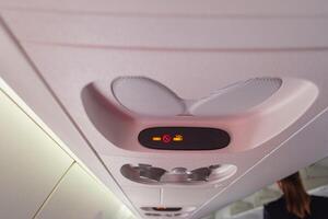 view of the overhead no smoking and buckle up seat belt sign or indicator on the interior cabin of an airplane in flight photo