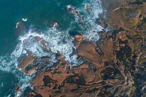 drone aerial overhead view of a stretch of rocky coastline photo