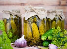 Delicious pickled homemade cucumbers in jars on a wooden background. Close-up. photo