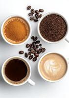 Three cups of coffee with ground coffee beans on a white surface and green leaves in the background photo