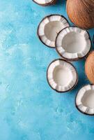 Fresh coconuts with opened shells arranged on a blue background photo