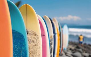 Colorful Surfboards Lined Up on Sandy Beach With Rocky Cliffs in Background photo