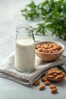 Almond milk in a glass jar surrounded by almonds and a soft cloth on a kitchen counter photo