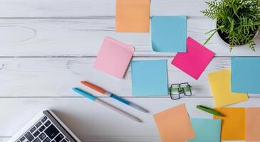 Laptop Surrounded by Colorful Sticky Notes on Wooden Desk photo