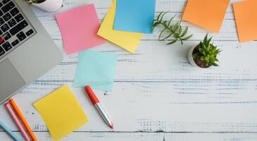 Laptop Surrounded by Colorful Sticky Notes on Wooden Desk photo