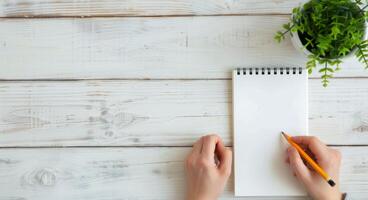 Person Writing In Notebook With Pencil Indoors During Daylight photo