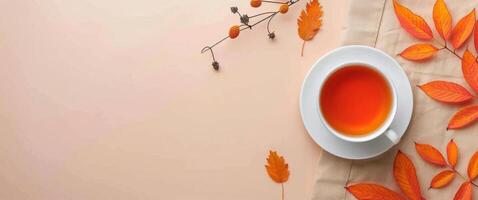 Autumn Leaves Surrounding a Cup of Tea on a Beige Surface photo