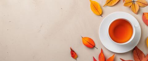Autumn Leaves Surrounding a Cup of Tea on a Beige Surface photo