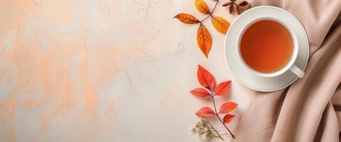 Autumn Leaves Surrounding a Cup of Tea on a Beige Surface photo