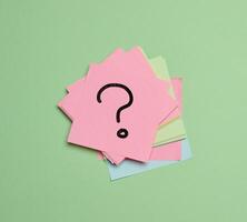 Drawn question marks on stickers, green background. Searching for truth and answering questions photo