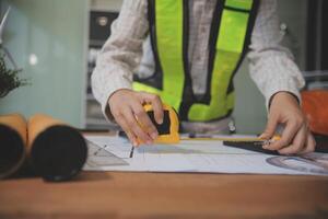engineer people meeting working and pointing at a blueprint in office for discussing. Engineering tools and construction concept photo