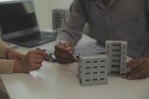 Real estate agent home sales broker is using a pen pointing to the house model and explains the business contract, rent, buy, mortgage, loan, or home insurance photo