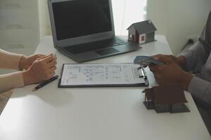 Real estate agent home sales broker is using a pen pointing to the house model and explains the business contract, rent, buy, mortgage, loan, or home insurance photo