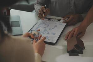 Real estate agent home sales broker is using a pen pointing to the house model and explains the business contract, rent, buy, mortgage, loan, or home insurance photo