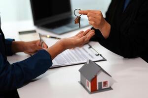 Estate agent giving house keys to client after signing agreement contract real estate with approved mortgage application form, concerning mortgage loan offer for and house insurance. photo