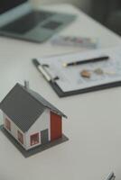 Real estate agent home sales broker is using a pen pointing to the house model and explains the business contract, rent, buy, mortgage, loan, or home insurance photo
