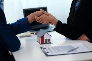 Estate agent shaking hands with customer after contract signature photo