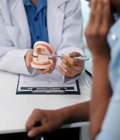 Dentist consultation - patient visit at the dental clinic office. Female dentist wearing dentures to explain teeth Recommend guidelines for orthodontics Dentist giving advice on patient's condition photo