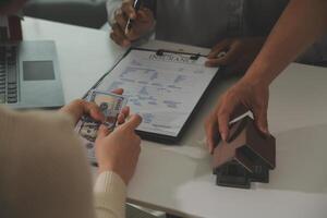 Real estate agent home sales broker is using a pen pointing to the house model and explains the business contract, rent, buy, mortgage, loan, or home insurance photo