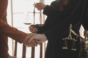 Lawyer shaking hands with a client making about documents, contracts, agreements, cooperation agreements with a female client at the lawyer's desk and a hammer at the table. photo
